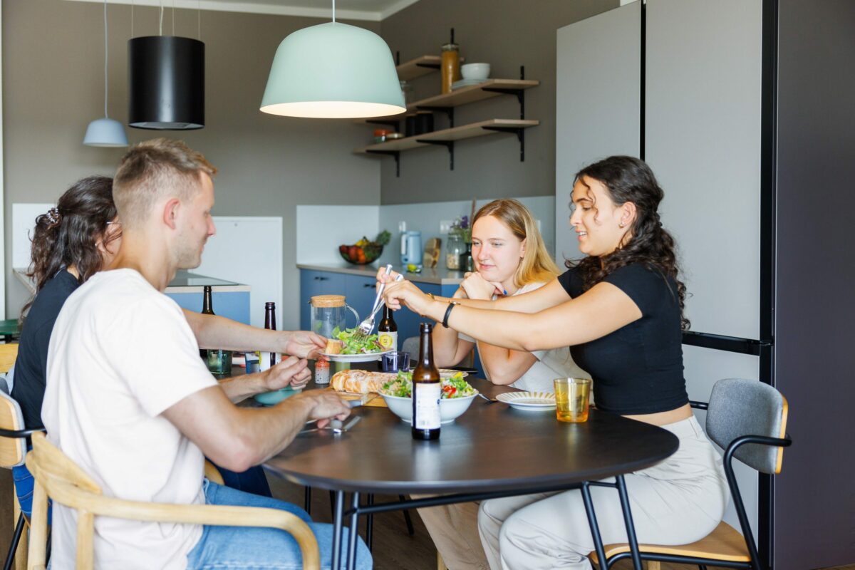 Mitbewohner, die sich in einer Gemeinschaftsküche in Aachen treffen und zu Mittag essen