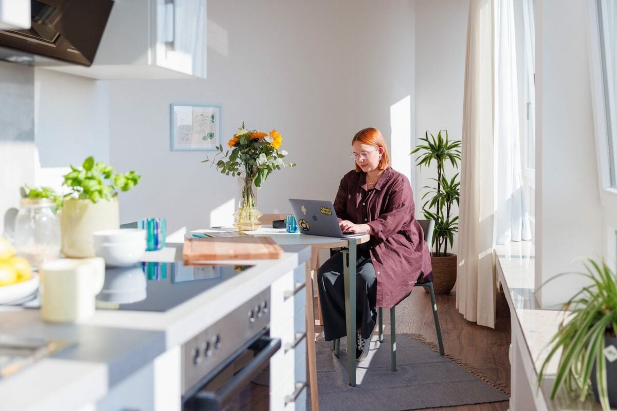 Mädchen arbeitet an ihrem Laptop in ihrer gemütlichen Wohnung