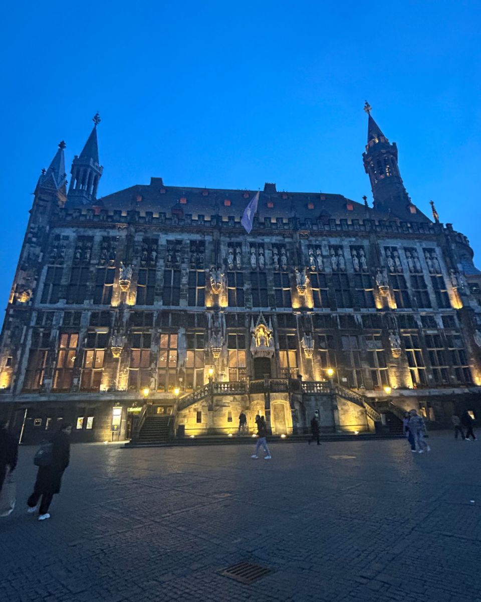 Illuminated facade of the Gothic Aachener Rathaus (City Hall) at dusk in the market square of Aachen, Germany.