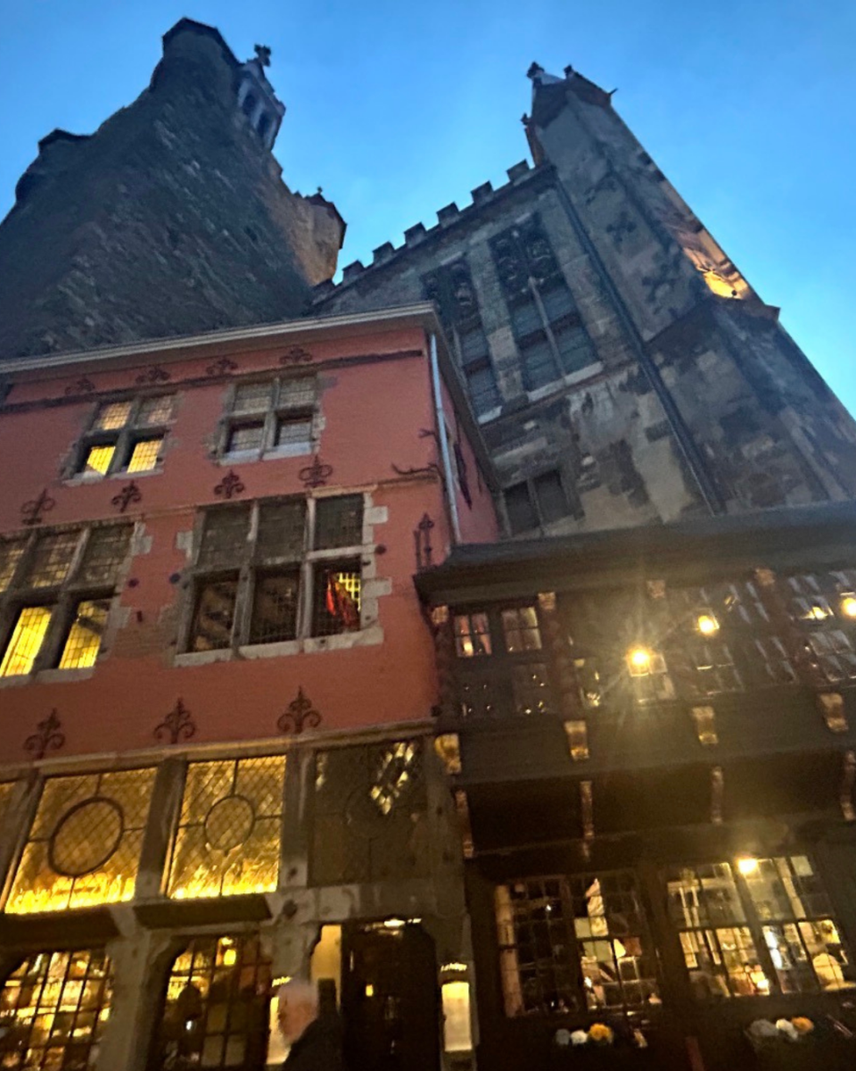 Night view of the historic pink-colored Ratskeller restaurant nestled beneath the towering Aachen Town Hall (Rathaus).