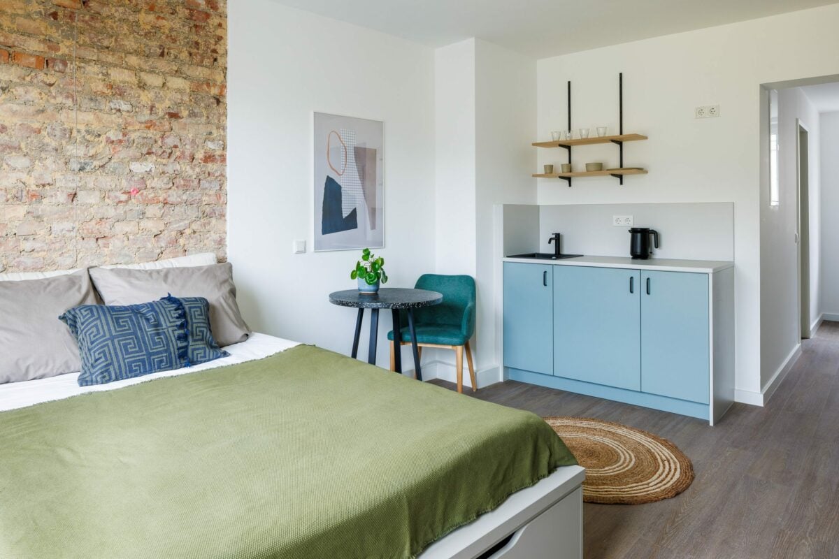 modern and clean hotel room with brick wall and blue kitchenette in Aachen